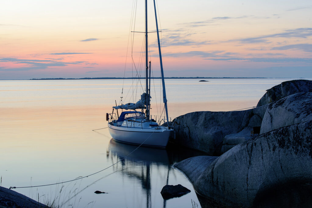 En segelbåt vid klippor i solnedgång