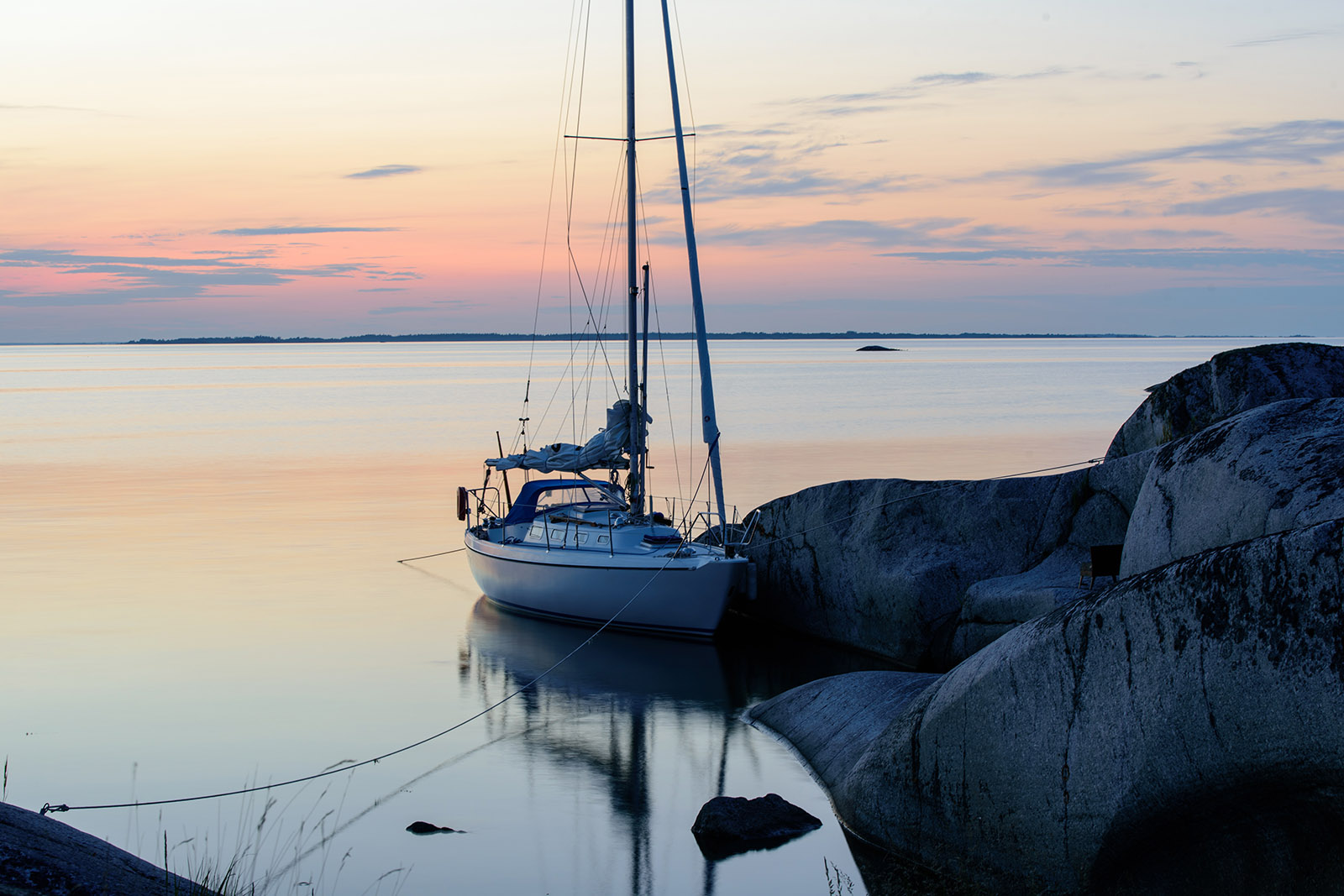 En segelbåt vid klippor i solnedgång