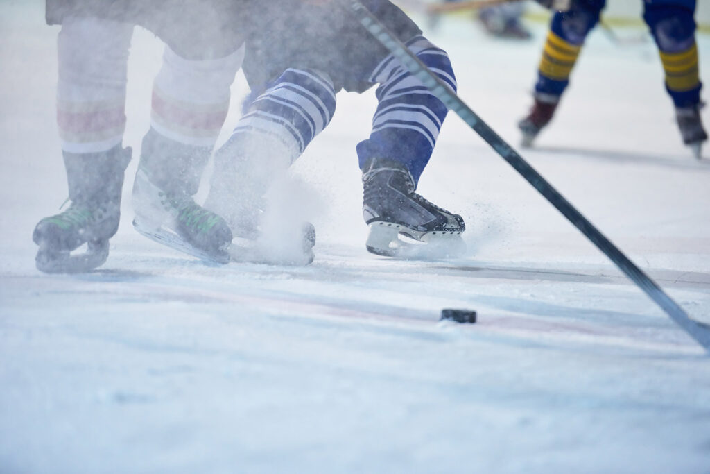 Närbild på ishockeypuck, klubbor och skridskor